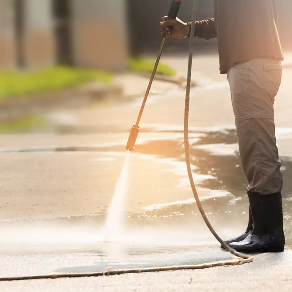 Person pressure washing an outdoor surface.