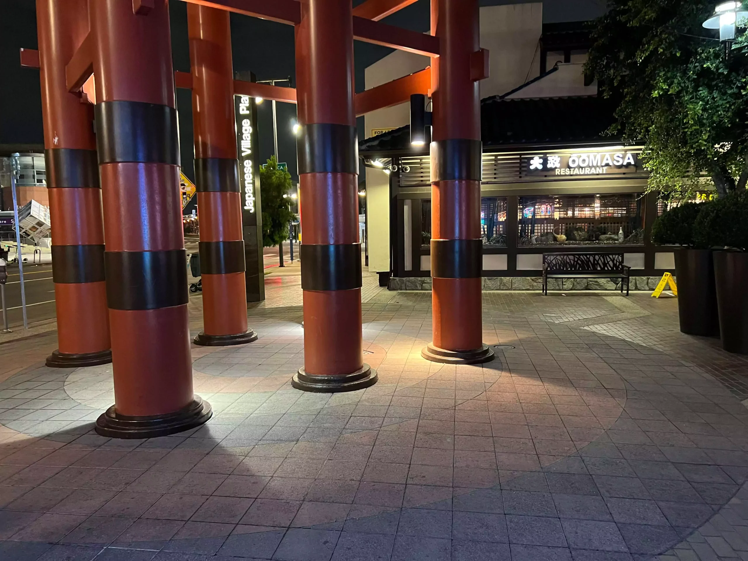 Empty sidewalk outside a closed store at night.